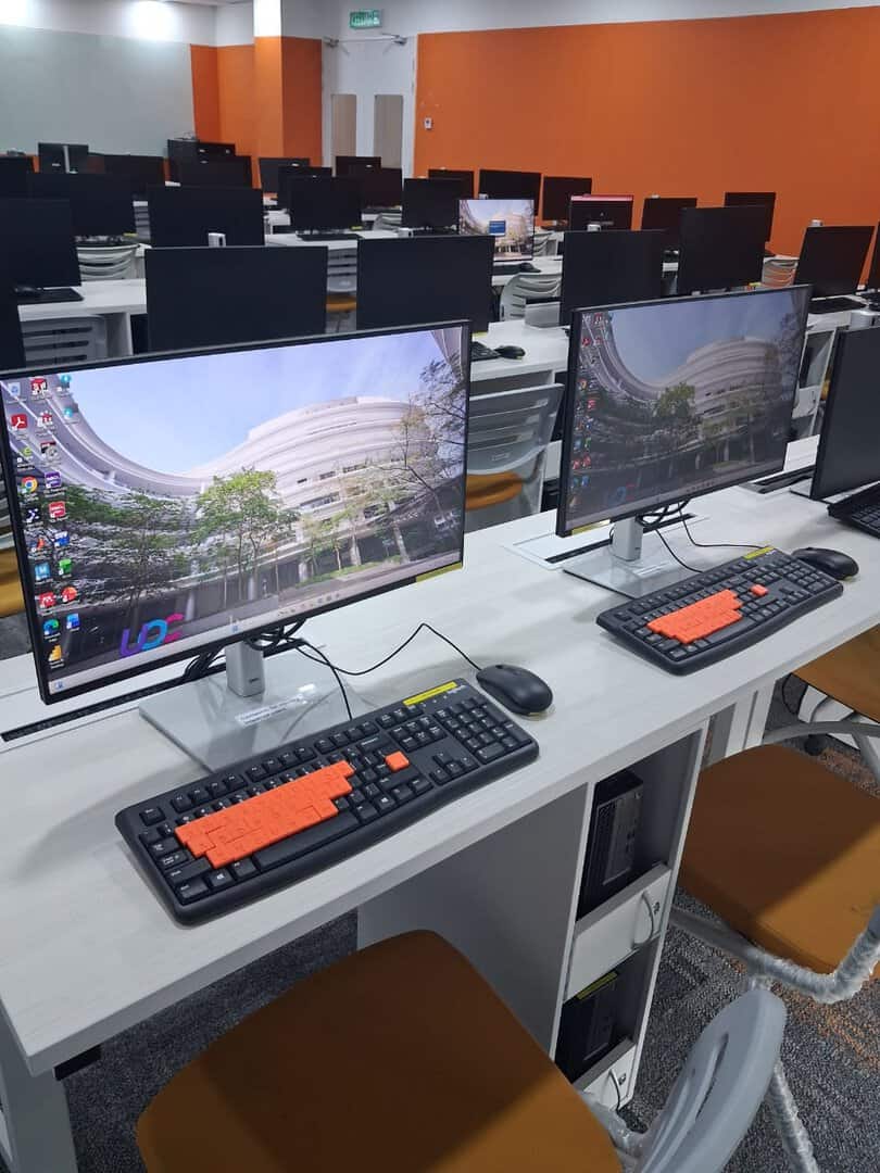 Assistive technology workstations with orange Braille keyboard overlays in the computer lab